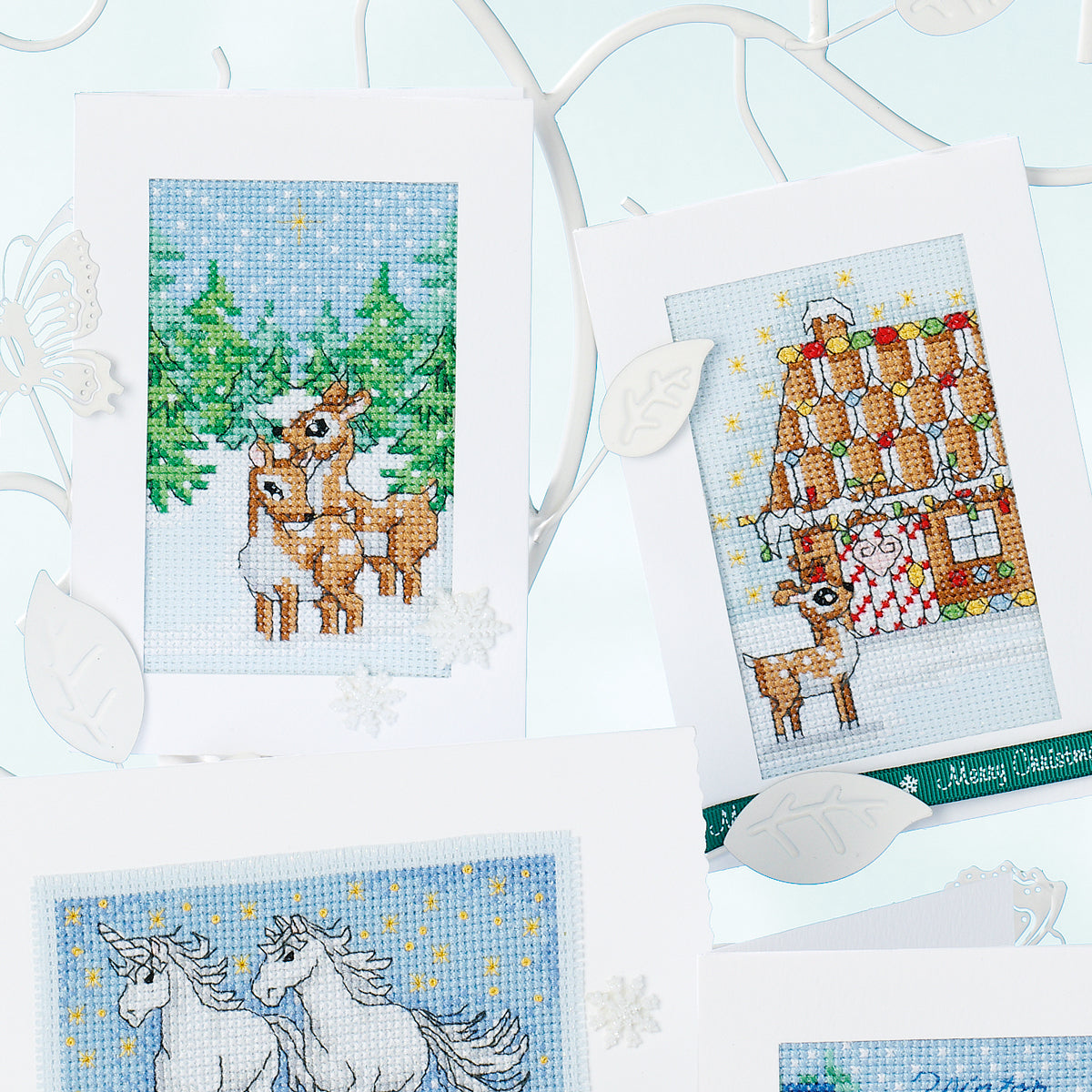 Cross-stitched cards with Christmas-themed designs on a white background