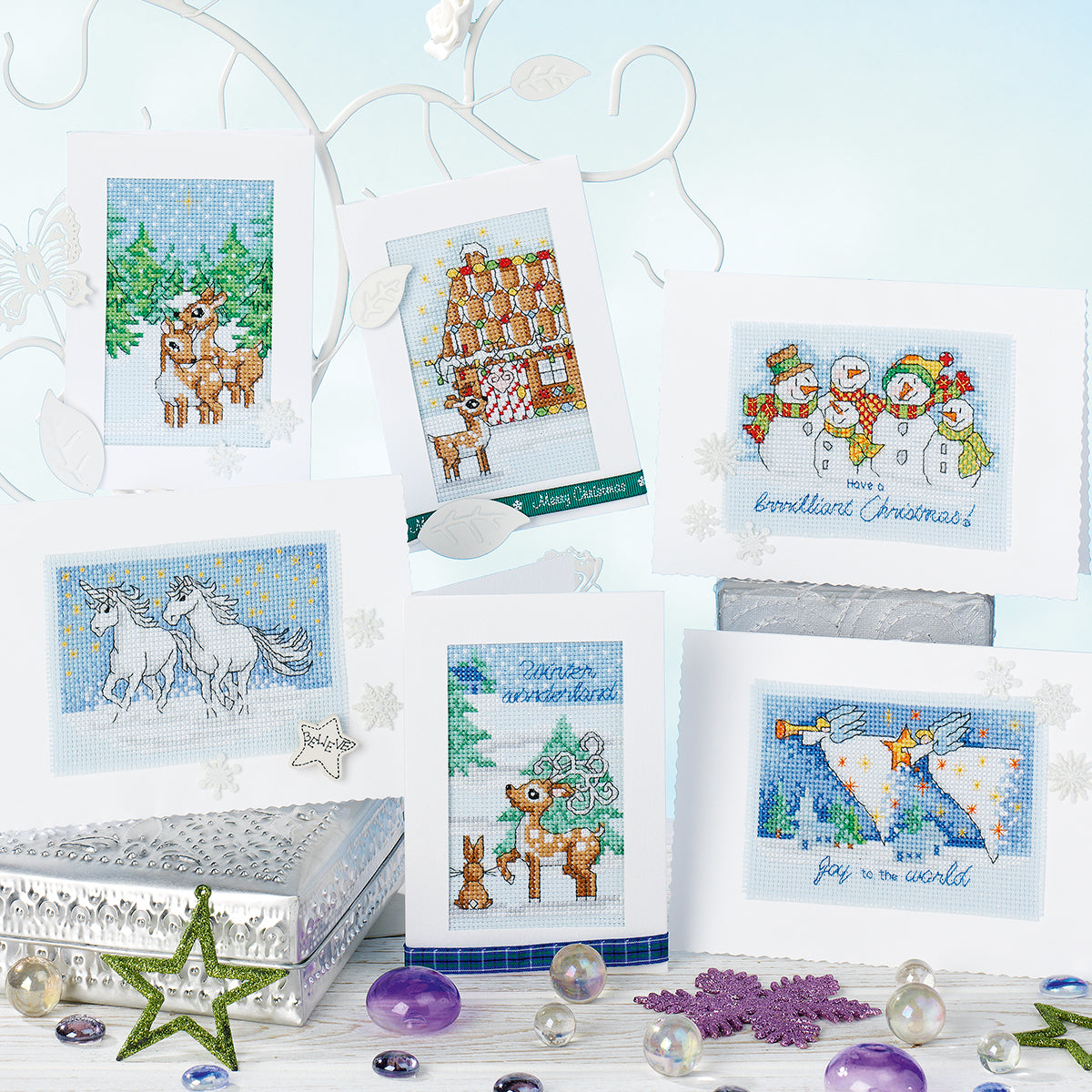 Collection of cross-stitched Christmas cards with various designs on a decorative stand.