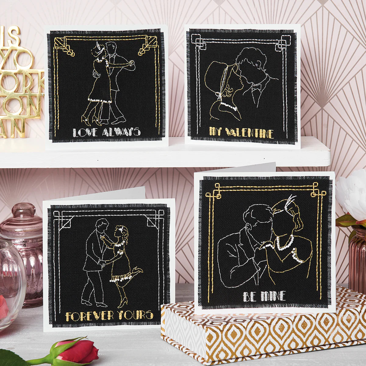 Four black and gold Valentine's Day cards with romantic illustrations on a decorative surface.