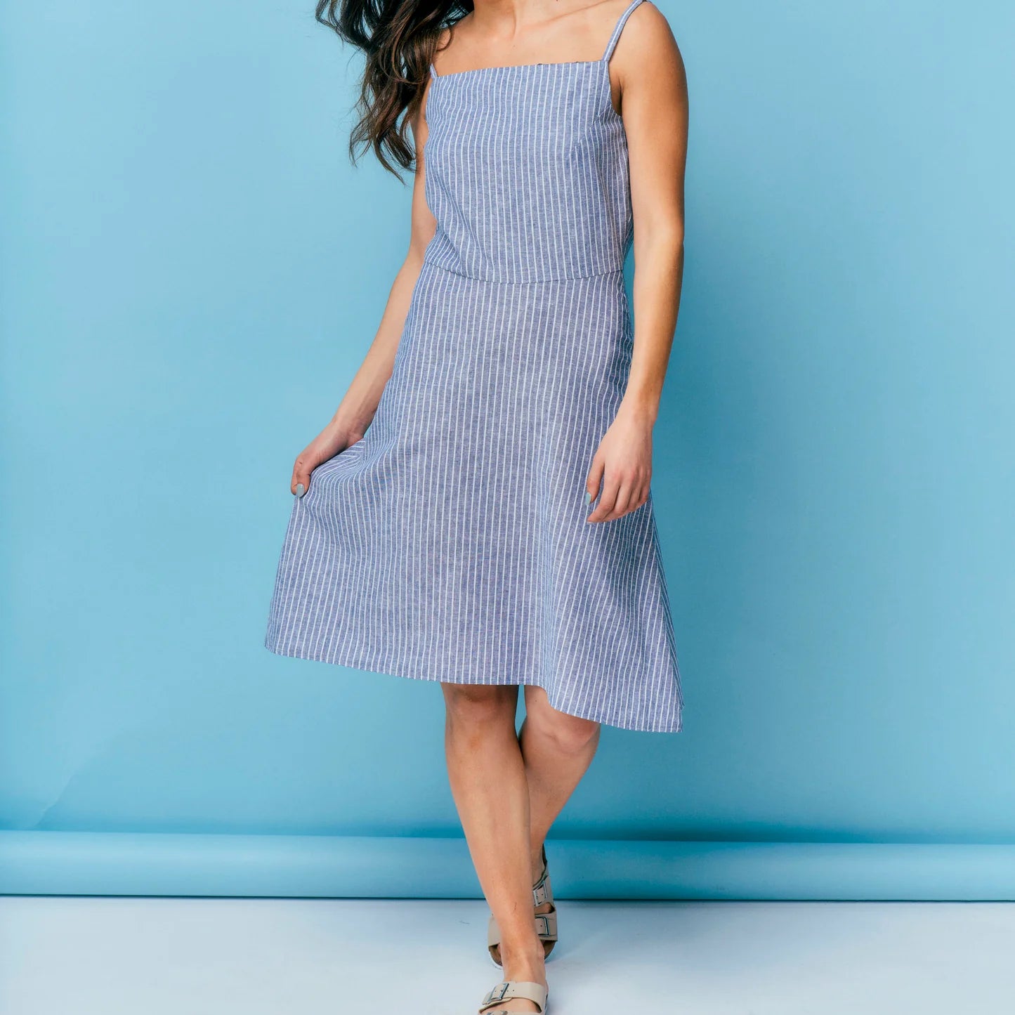 Woman wearing a blue and white striped dress against a blue background