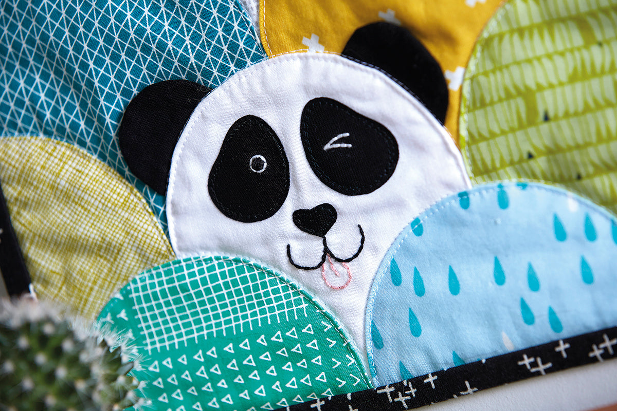 A clamshell Panda quilt featuring a cheeky Panda face with its tounge sticking out and one eye winking. 