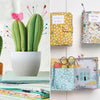 Collage of sewing-themed items including a cactus-shaped pin cushion, fabric books, and a fabric house with scissors.