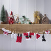 Knitted Santa Claus outfit on a clothesline with Christmas decorations in the background.