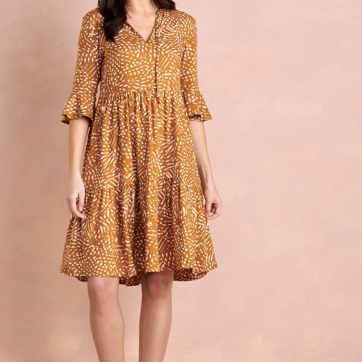 Woman wearing a patterned dress on a beige background