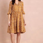 Woman wearing a patterned dress on a pink background