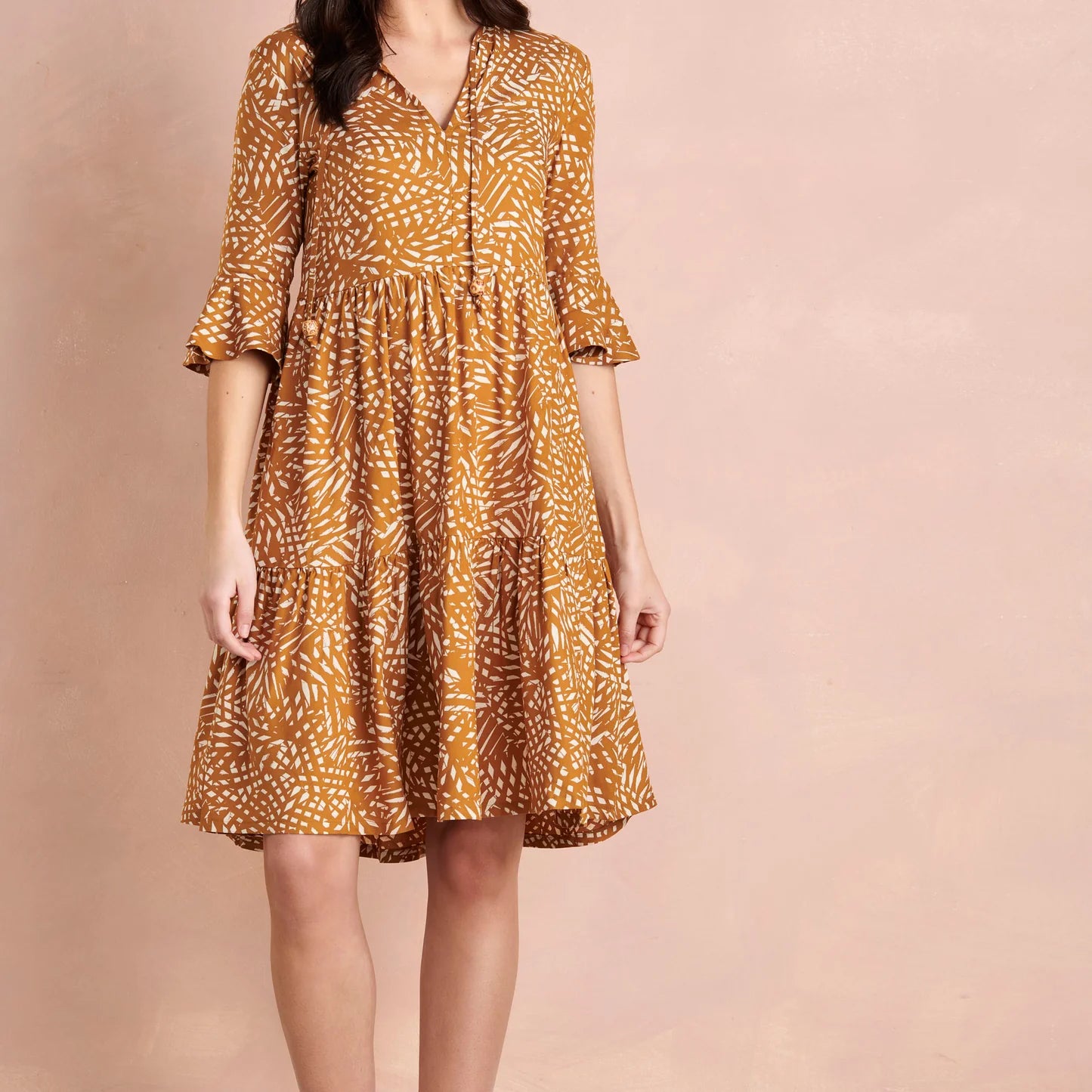 Woman wearing a patterned dress on a pink background