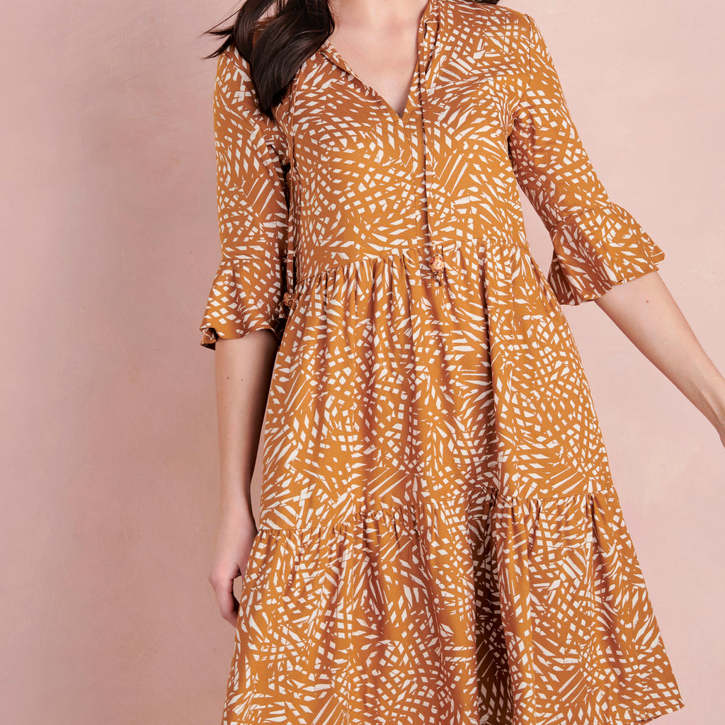 Woman wearing a patterned dress against a plain background