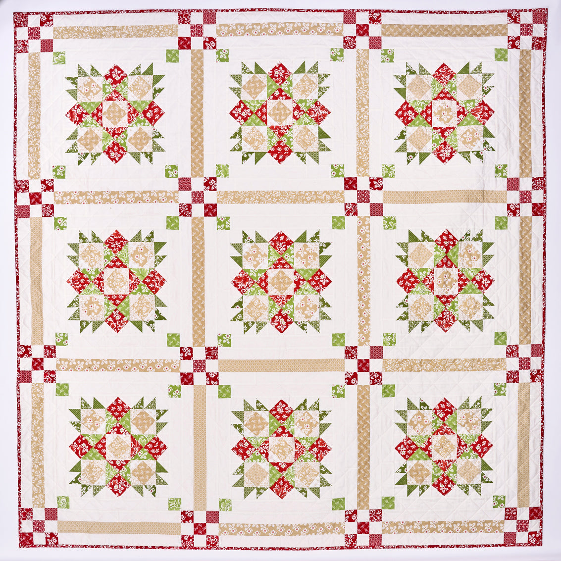 Quilt with floral pattern in red, green, and beige on a white background
