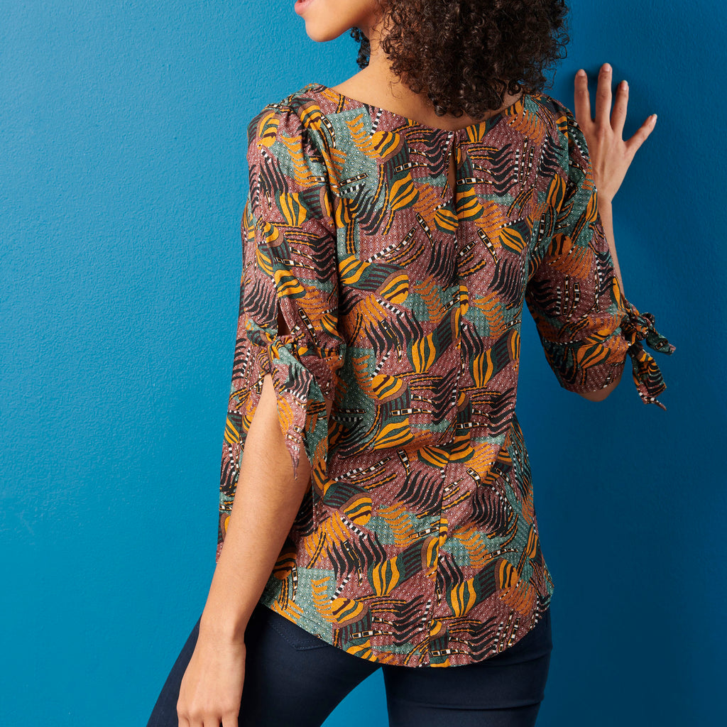Woman wearing a patterned blouse against a blue background