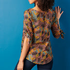 Woman wearing a patterned blouse against a blue background