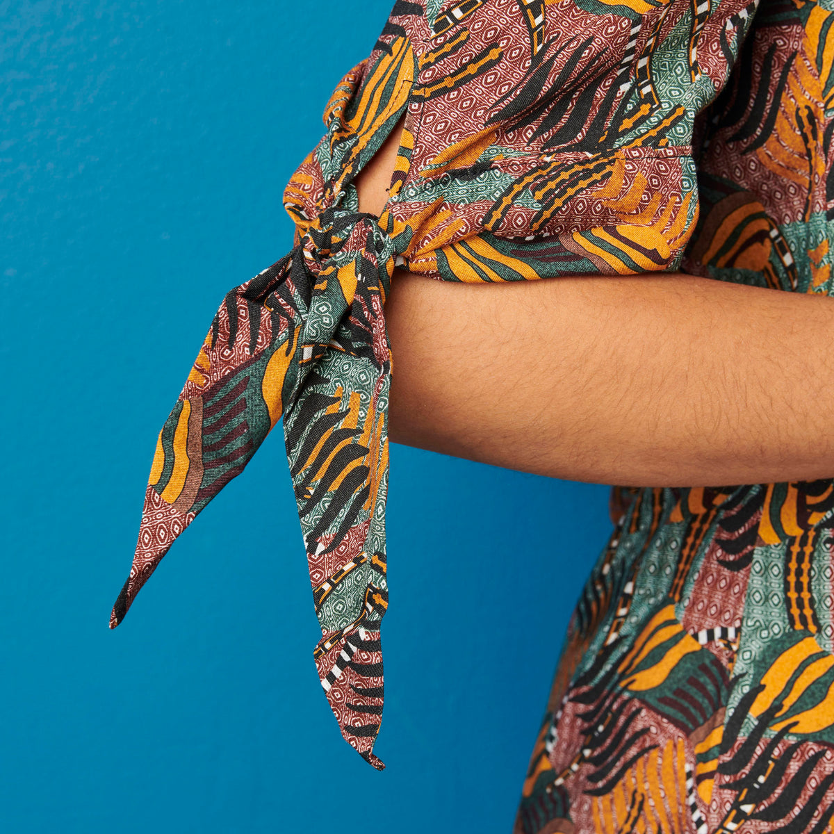 Patterned fabric tied around a person's arm against a blue background