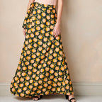 Person wearing a long skirt with peach pattern against a plain background