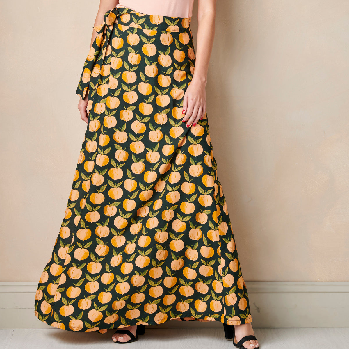 Person wearing a long skirt with peach pattern against a plain background