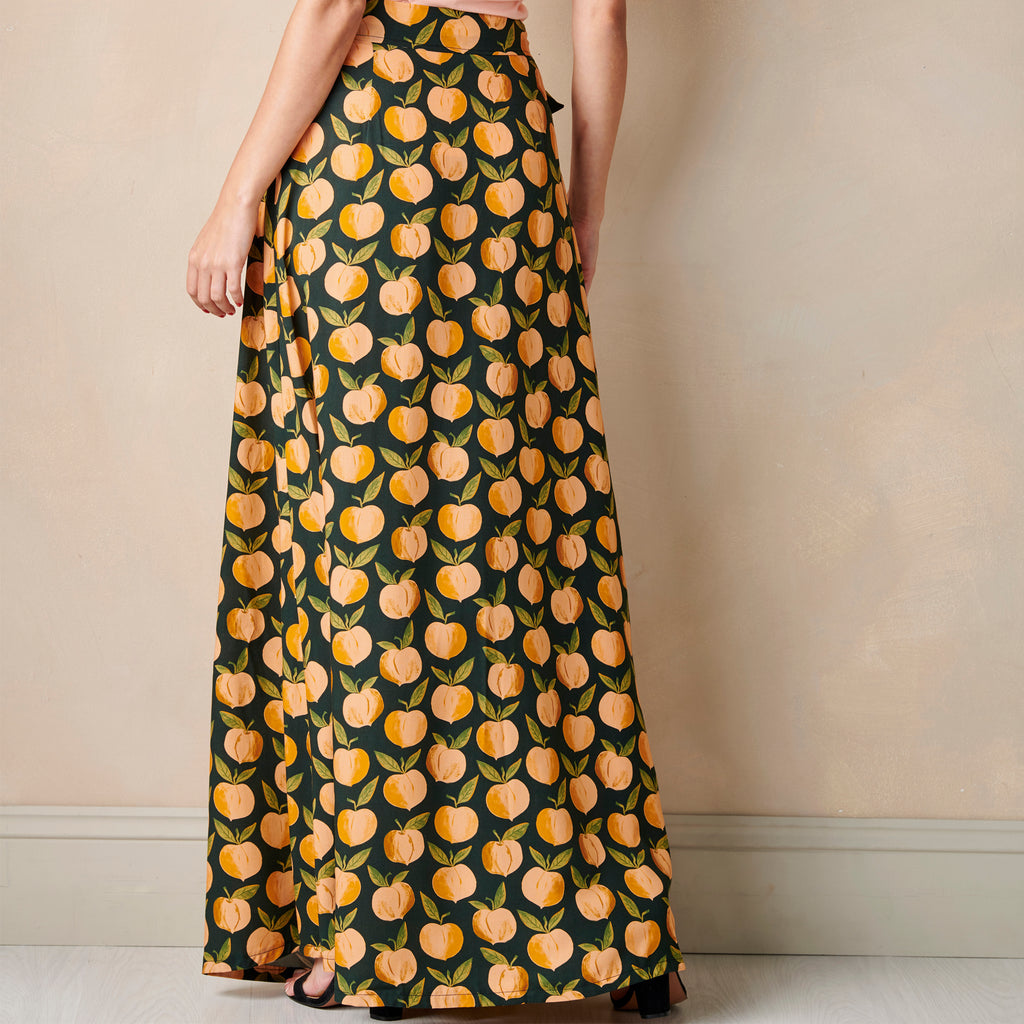 Long dress with peach pattern worn by a person against a beige wall.