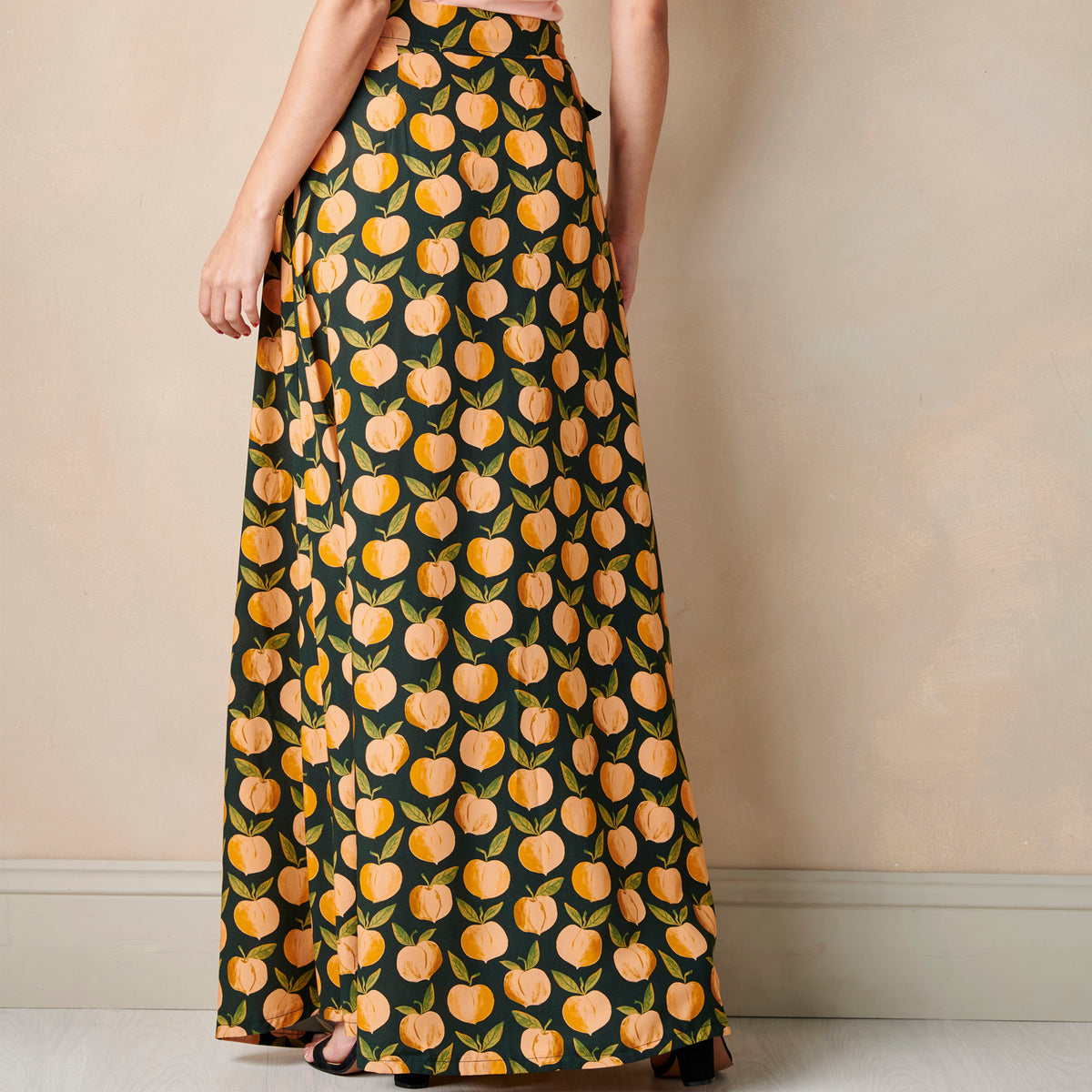 Long dress with peach pattern worn by a person against a beige wall.